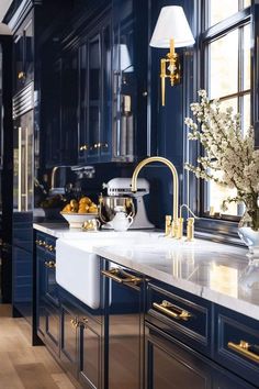 a kitchen with blue cabinets and white counter tops, gold pulls on the faucet