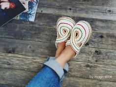 a person's feet wearing crocheted slippers on top of a wooden floor