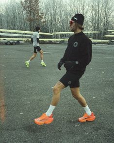 two men are playing soccer in an open field with one man wearing bright orange shoes