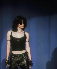 a woman in black leather pants and crop top posing for the camera with her hands on her hips