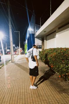 a man is standing on the sidewalk with his back to the camera and looking at something