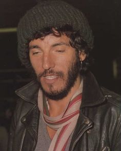 a black and white photo of a man with a beard wearing a beanie hat