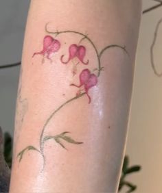 a close up of a person's arm with tattoos on it and pink flowers