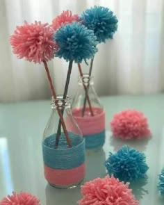 three vases with pink and blue pom - poms sitting on a table