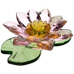 a glass flower sitting on top of a green leafy plant with water lilies