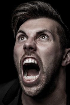 a man with his mouth wide open in front of the camera, making an angry face