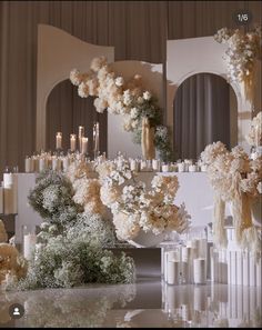 a table topped with lots of white flowers next to tall vases filled with candles