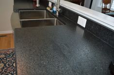 a black counter top in a kitchen next to a sink