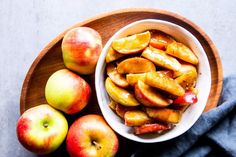 apples are in a bowl on a wooden plate