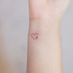 a small heart with an arrow tattoo on the wrist