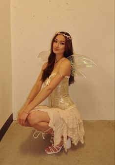 a woman dressed as a fairy sitting on the floor