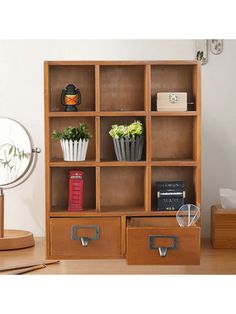 a wooden bookcase filled with lots of books and plants next to a mirror on top of a hard wood floor