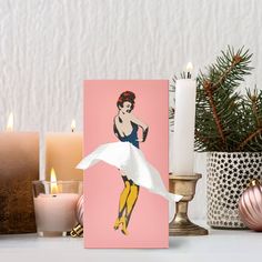 a pink card with a woman's image on it next to candles and other decorations