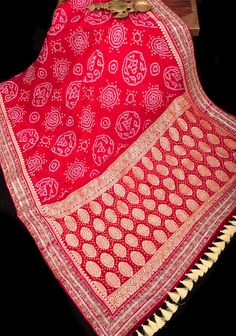 Elevate your elegance with this Authentic Sarkam Bandhej Silk Georgette Saree in a mesmerizing shade of red, adorned with a delicate Gotta Patti border. Crafted with precision and finesse, this saree features the traditional Sarkam Bandhej technique, known for its intricate tie-and-dye patterns that create a unique and mesmerizing texture. The rich red hue exudes vibrancy and passion, making a bold statement wherever you go. Adding to its allure is the handwork trim, meticulously adorned with in Regal Elegance, Dye Patterns, Silk Tassels, Gotta Patti, Shade Of Red, Saree Blouses, Georgette Saree, Georgette Sarees, Shades Of Red