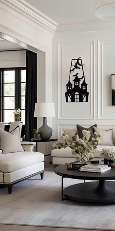 a living room filled with white furniture and black accents on the walls, along with large windows