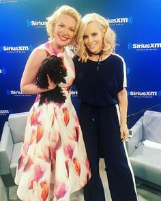 two women standing next to each other in front of a blue wall with the sirius logo