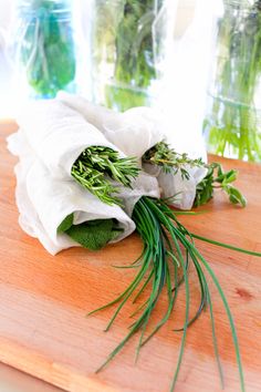 herbs are wrapped in white paper on a cutting board