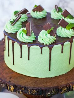 a green cake with chocolate icing and mint sprinkles on a wooden platter