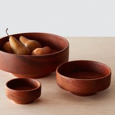 three wooden bowls with pears in them on a table