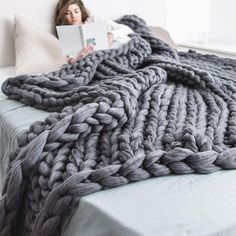 a woman laying in bed under a gray blanket