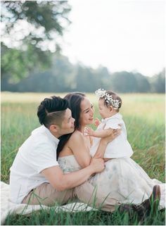 a man and woman are sitting in the grass with a baby