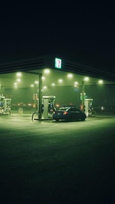 a gas station at night with cars parked in the lot and no one around it