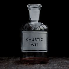 a glass bottle filled with liquid sitting on top of a wooden table next to a black background