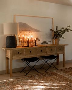 a wooden table topped with candles next to a painting