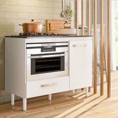 a kitchen with white cabinets and an oven in the center, next to a wooden floor