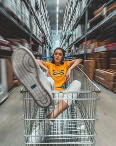 a woman sitting in a shopping cart with her feet on the basket and looking at the camera