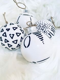 three white ornaments with black and white designs on them sitting on a fur covered surface