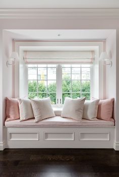 a window seat with pillows on it in front of a window