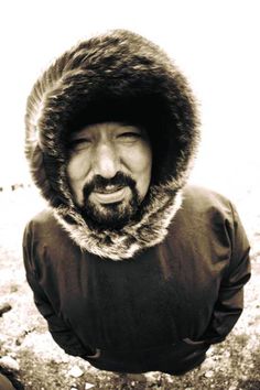 a man wearing a fur hat and jacket with his mouth open in front of the camera