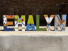 the word farm spelled with wooden letters in front of a brick wall and cement block