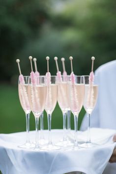 there are many wine glasses with pink straws in them on the tray and one is filled with champagne