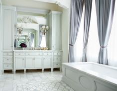 a large bathroom with white cabinets and marble flooring, along with an ornate chandelier