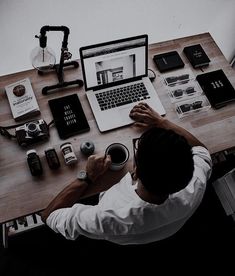 a person sitting at a desk with a laptop and various other items on the table