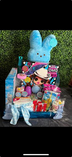 a blue box filled with toys on top of a black cloth covered floor next to a green wall