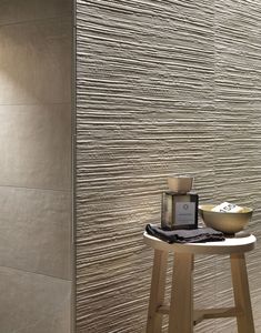 a table with a bowl on top of it next to a tiled wall in a bathroom