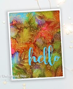 a card with the word hello written in blue on top of colorful leaves and stars