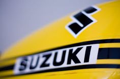 the suzuki logo is on the side of a yellow sports bike with black and white stripes