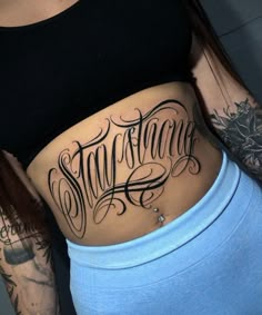 a woman's stomach with the word stay strong written on it and an arrow tattoo