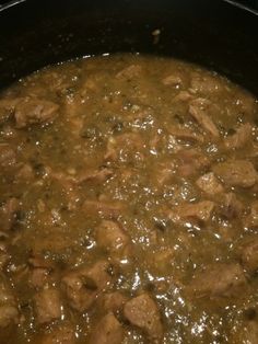 meat and vegetable stew in a black pot on the stove top, ready to be cooked