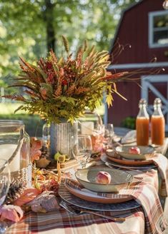 the table is set with plates, silverware and orange juice in front of a barn