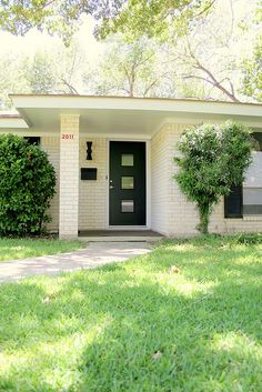 a white house with black door and green grass on the front lawn in front of it