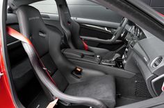 the interior of a red car with black leather seats