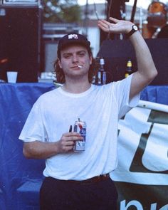 a young man holding up a beer bottle in front of his face while standing next to a stage