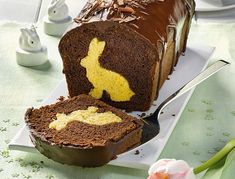 a piece of chocolate cake with yellow frosting and a bunny cut in half on a plate