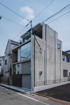 the building is made out of concrete and has glass windows on each side, along with power lines above it