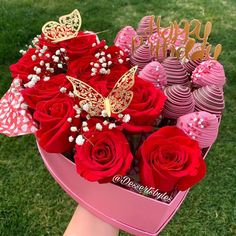 a pink heart shaped box filled with red roses and chocolate covered strawberries in front of a happy birthday sign